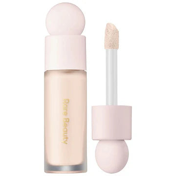 Concealer bottle with doe-foot applicator open, showing creamy texture on a soft backdrop.