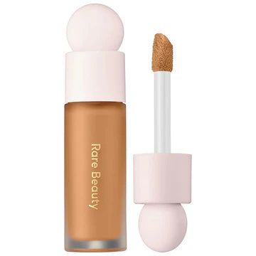 Model applying concealer with a sponge, highlighting a natural finish on cheeks and under-eyes.