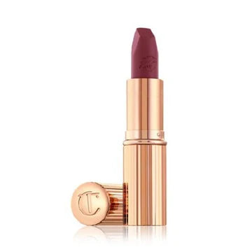 Flat lay of the lipstick beside Lip Cheat in Love Trap on a vanity setup with rose petals

