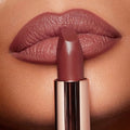 Close-up of lips wearing the matte lipstick in a warm nude shade, showing smooth finish

