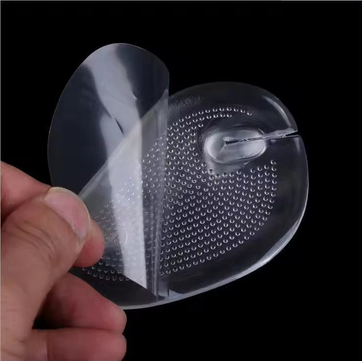 Clear plastic shoe insert held by a hand against a black background