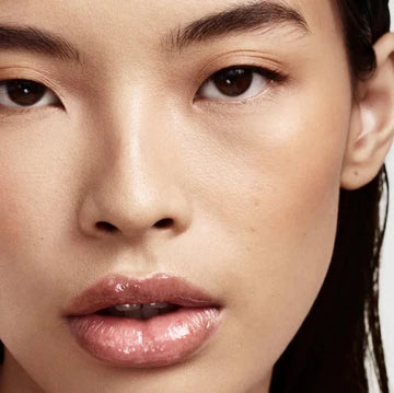 Close-up of lip luminizer tube with a vibrant, glossy finish, highlighting its plumping and hydrating formula.

