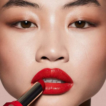A model applying the lipstick, showcasing the vibrant shade and its moisturizing effect.

