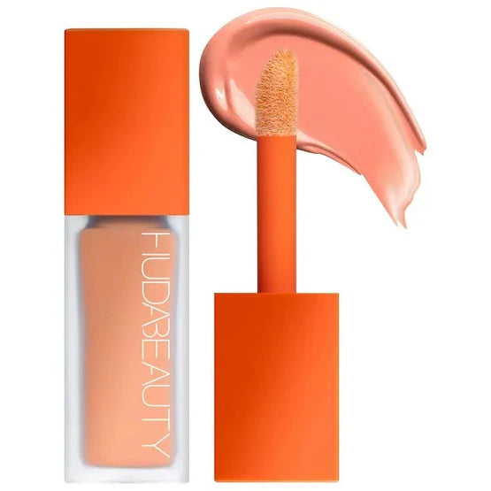 HUDA BEAUTY FauxFilter Brightening Under Eye Color Corrector in Peach shade, featuring text highlighting its lightweight, blendable formula that's crease-proof and transfer-resistant for 12 hours of wear. The product description emphasizes its longwear capabilities and fragrance-free formula.