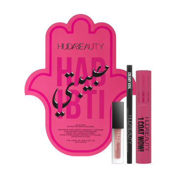 Huda Beauty Habibti Eye & Lip Set featuring the 1 Coat WOW! Volumizing Mascara, Creamy Kohl eyeliner, and Liquid Matte Lipstick in a luxurious travel-friendly kit. The packaging displays the brand's signature gold-and-pink aesthetic with product names in English and French