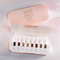 Huda Beauty's KAYALI Discovery Layering Set featuring eight 1.5ml/0.05 fl.oz luxury perfume miniatures for custom scent combinations. The minimalist packaging displays elegant 'KAYALI' branding in sleek typography, perfect for fragrance enthusiasts.