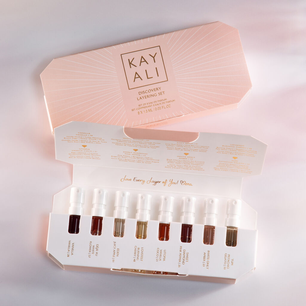 Huda Beauty's KAYALI Discovery Layering Set featuring eight 1.5ml/0.05 fl.oz luxury perfume miniatures for custom scent combinations. The minimalist packaging displays elegant 'KAYALI' branding in sleek typography, perfect for fragrance enthusiasts.