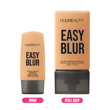 Close-up of Huda Beauty Mini Easy Blur Natural Airbrush Foundation in shade Creme Brulee, showing the 10ml travel-size tube with gold accents and product name visible.