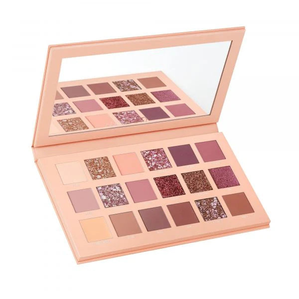 HUDA BEAUTY The New Nude Eyeshadow Palette showing nine shades including DARE (rich plum), OPINE (soft mauve), PLAY (champagne shimmer), FANTASY (peachy nude), LOVE BITE (deep berry), SPARKED (golden bronze), LACE (pale ivory), DANDERAM (warm terracotta), and TOALE (cool taupe) in rectangular pans with shade names visible beneath each