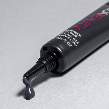 Close-up of HUDA BEAUTY Waterproof Lash Glue packaging showing brand name, product size (0.28 fl oz), and manufacturing origin (Made in China