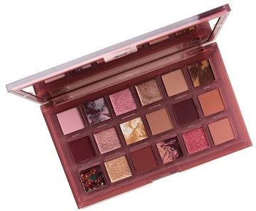 Close-up of HUDA BEAUTY's Naughty Nude Palette showing nine eyeshadows named FILTHY, PASSION, SNAMBLESIS, PLEASE ME, HYPNOTIC, HARD, QUIVANED, IRRESISTIBLE, and FLOWER POWER in neutral tones