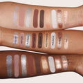 Arm swatches of the Huda Beauty Icy Nude eyeshadow palette on three different skin tones, showcasing shimmery, matte, and metallic shades including Iced Out, High Life, Platinum, Unapologetic, Faux Fur, Gold Standard, Avalanche, Aurora, and VVS