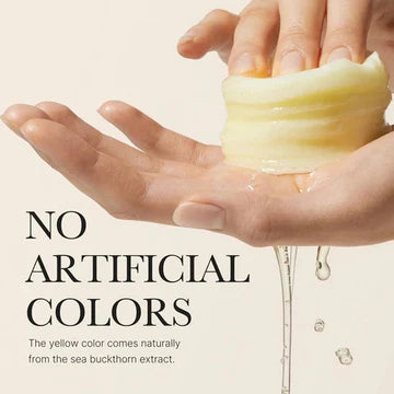 Hand holding a yellow bar of soap with text about natural coloring from sea buckthorn extract.