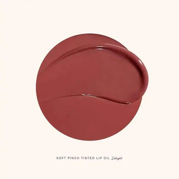 Close-up of Soft Pinch Lip Oil applicator showing glossy rose brown tint.


