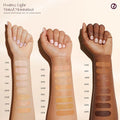 Swatches of tinted moisturizer shades on multiple skin tones, showcasing the inclusive shade range.

