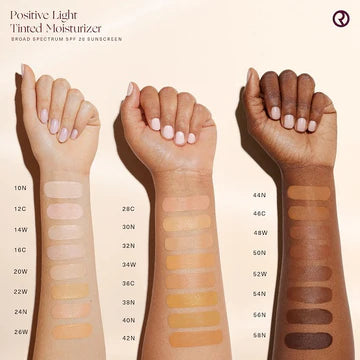 Swatches of tinted moisturizer shades on multiple skin tones, showcasing the inclusive shade range.

