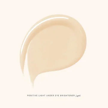 Model applying brightener under the eyes for a fresh, radiant finish.

