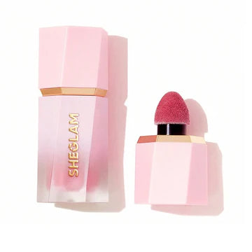 Front and side view of SHEGLAM Color Bloom Dayglow Liquid Blush bottle in On Point shade, featuring a sleek transparent tube with metallic gold accents that shows the blush's shimmering liquid formula inside. The minimalist design displays the brand logo and product name in bold typography