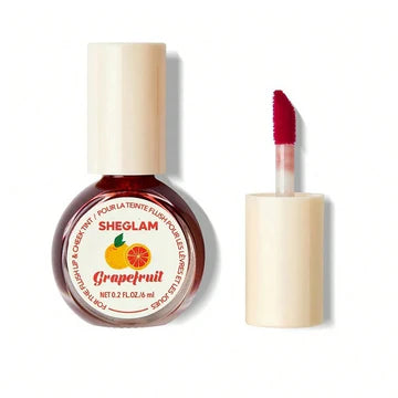 Close-up of SHEGLAM For the Flush Lip & Cheek Tint in Fruit Punch shade, featuring a liquid tube packaging with red gradient color and visible brand logo, showcasing the vibrant pink-red tint