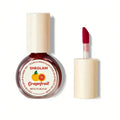 Close-up of SHEGLAM For the Flush Lip & Cheek Tint in Fruit Punch shade, featuring a liquid tube packaging with red gradient color and visible brand logo, showcasing the vibrant pink-red tint