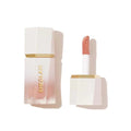 Close-up of SHEGLAM Glow Bloom Liquid Highlighter packaging showing a sleek glass bottle with a dropper applicator and silver cap. The minimalist design features the product name in clean typography against a clear background, emphasizing its dewy, luminous formula