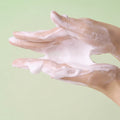 Hands with soap suds on a light green background